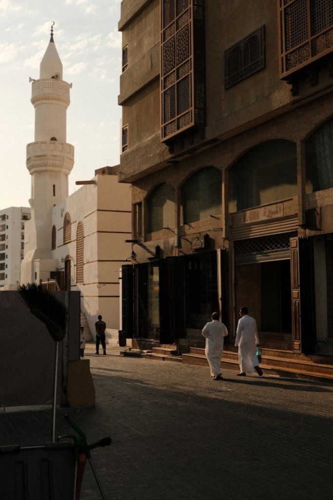 A group of men walking down a street next to tall buildings
Arab Saudi