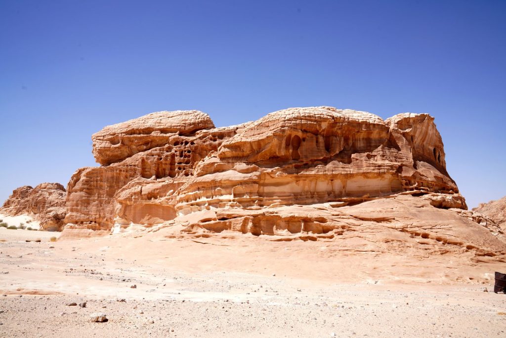 Imposing rock formation in a desert landscape under clear blue skies, perfect for travel imagery.